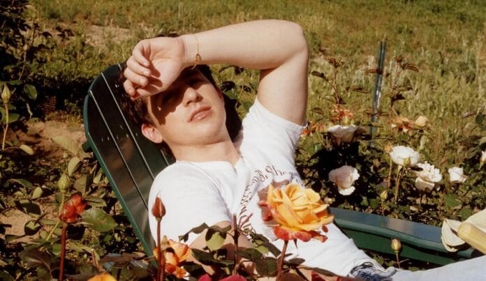Charlie Puth a kertben ül rózsák között